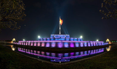 Tower and stone walls shimmering colors around the outside royal Imperial palace at night in Hue, Vietnam.