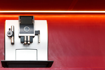 coffee machine stands against a red wall