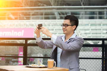 Happy Asian businessman selfie using phone at cafe