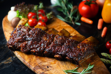BBQ beef ribs steak served with a hot chili pepper and fresh tomatoes on an old vintage wooden cutting board