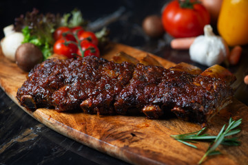 BBQ beef ribs steak served with a hot chili pepper and fresh tomatoes on an old vintage wooden cutting board