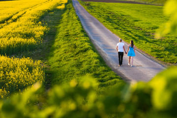 Obraz premium Beauty family man and woman walk and see to yellow canola field in summer