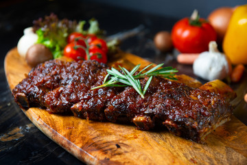 BBQ beef ribs steak served with a hot chili pepper and fresh tomatoes on an old vintage wooden cutting board