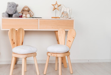 2 chairs with bunny ears in the children's room and a table with toys