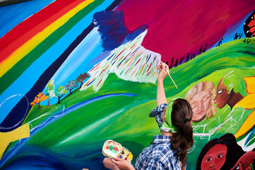 Frau malt Friedenstaube auf bunte Wand