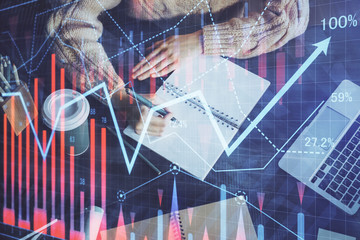 Forex graph on hand taking notes background. Concept of research. Double exposure