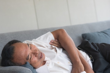 Obraz na płótnie Canvas Senior Asian man sleeping on couch with happy smile on face and relaxing from tiredness