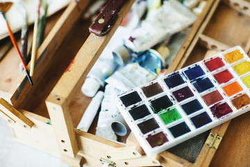 Close up of wooden suitcase artist with watercolor paint, brushes and artistic tools. Art concept