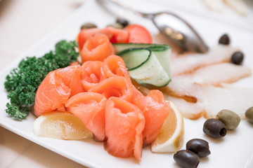 at the banquet there is a plate with red fish, olives and olives, decorated with greens