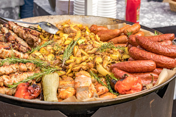 Fried potatoes with fried sausages in a pan. Dish fried potatoes with sausages, onions, garlic, cumin, pepper and seasonings.
