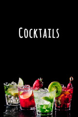 Four colorful tasty alcoholic cocktails in a row at the bar stand. Luxury vacation concept. Vertical, isolated on black. Cocktails wording