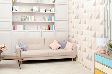 Pastel-coloured interior with beige sofa and built-in bookcase