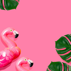 Creative summer beach concept. Inflatable pink mini flamingo and tropical leaf monstera on pink background, pool float party. Flat lay copy space. Flamingo Trend Inflatable Toy. Summer background