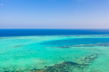 Fototapeta na wymiar Atoll and blue sea, view from above. Seascape by day. Turquoise and blue sea water.