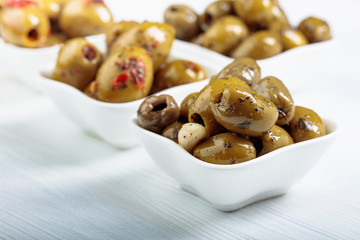 Spiced green olives in oil on a  wooden table.