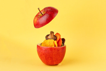 Healthy vegetable chips yellow sweet potato purple sweet potato carrot green radish green beans and shiitake mushrooms in hollow red apple yellow background