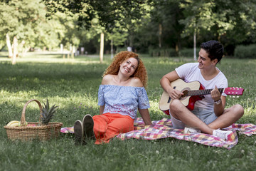 Red hair woman and her boyfriend sitting on a blanket