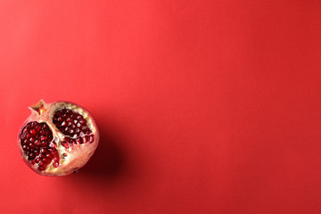 Ripe tasty red pomegranate fruit in a cut on a bright red paper background. top view. space for text