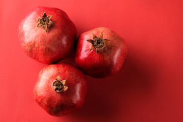 Ripe tasty red pomegranate fruit on a bright red paper background. view from above.