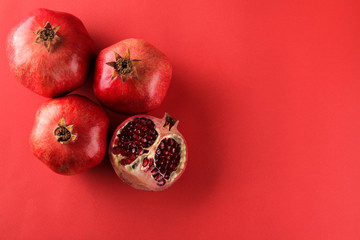 Ripe tasty red pomegranate fruit in a cut on a bright red paper background. top view. space for text