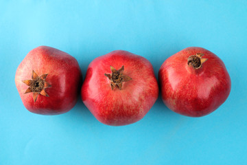 Ripe tasty red pomegranate fruit on a bright blue paper background. view from above.