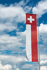 Swiss flag banner under an expressive blue sky with white cumulus clouds and copy space