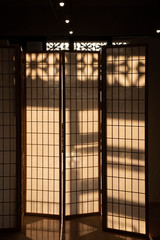 Calm and peaceful traditional Japanese sliding screen with wooden frame, with an afternoon sunlight.