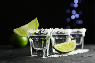 Tequila shots with salt and lime slices on black background