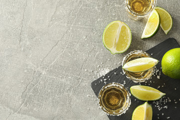 Tequila shots with salt and lime slices on grey background