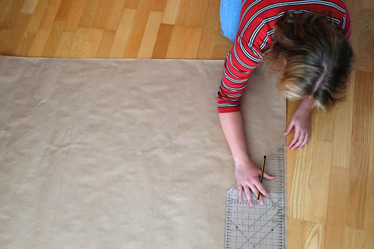 teenage girl measuring and drawing on brown kraft paper on the floor