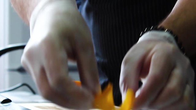 The cook puts a slice of orange on cheesecakes with sweet sauce