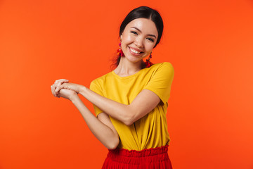 Excited happy young woman posing isolated over orange wall background.