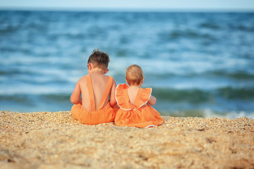 boy and girl near the sea in the same orange clothes
