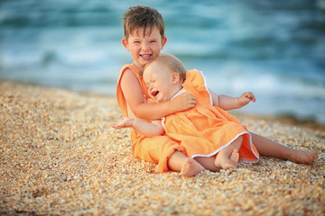Fototapeta na wymiar boy and girl near the sea in the same orange clothes