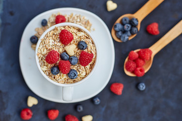 Raspberries and blueberries on blue background. Cereals.