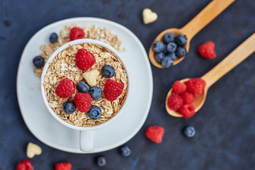 Raspberries and blueberries on blue background. Cereals.