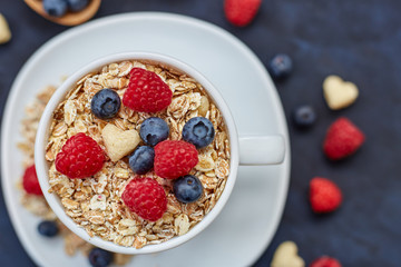 Raspberries and blueberries on blue background. Cereals.