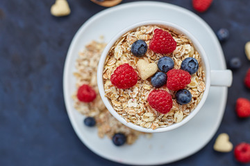 Raspberries and blueberries on blue background. Cereals.