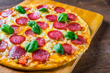 Pepperoni Pizza with Mozzarella cheese, salami, Tomato sauce, pepper, Spices and Fresh basil. Italian pizza on wooden table background