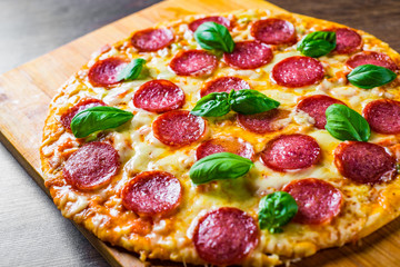 Pepperoni Pizza with Mozzarella cheese, salami, Tomato sauce, pepper, Spices and Fresh basil. Italian pizza on wooden table background