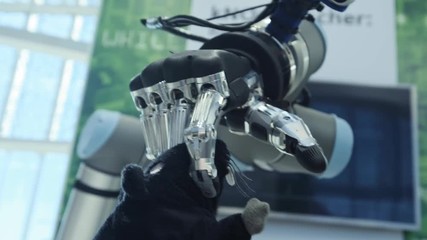 New technologies among us. The hand of the robot takes a soft toy in the shape of a mouse by the tail. Future today - Powered by Adobe