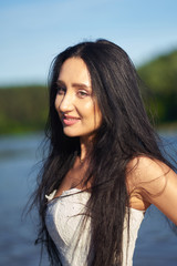 Portait of young smiling pretty brunette woman in white wedding dress outdoors