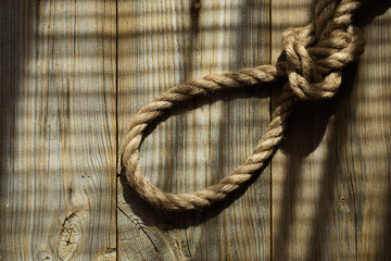 Rope with a knot on a wooden surface.