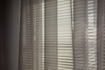Gray transparen curtains at wide jalousie window.