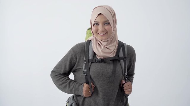Portrait of beautiful hijab traveller with backpack smile looking at camera with isolated background