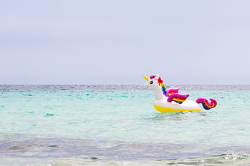 Rainbow inflatable unicorn in the sea. Enjoy the summer. Vacation and travel concept. Copy space