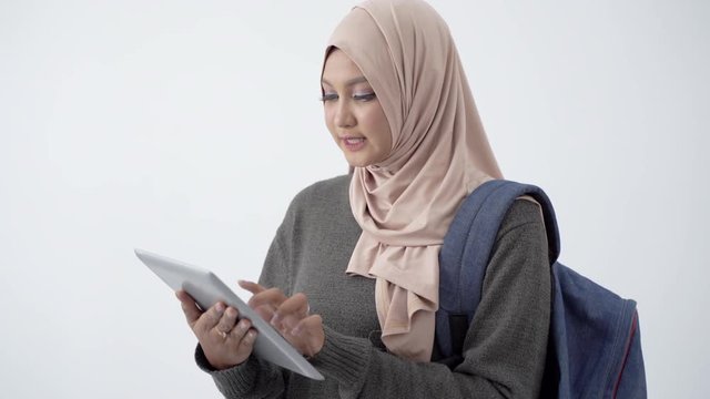 College student using tablet to study and carrying a bag at isolated background