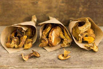 Dry mushroom chips in paper bags wooden background.