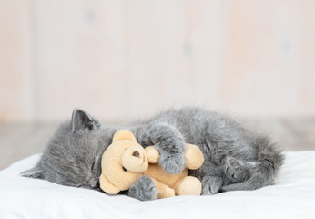 Sleeping kitten hugs toy bear © Ermolaev Alexandr