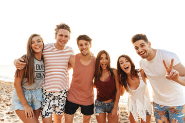 Group of happy friends standing at the beach together